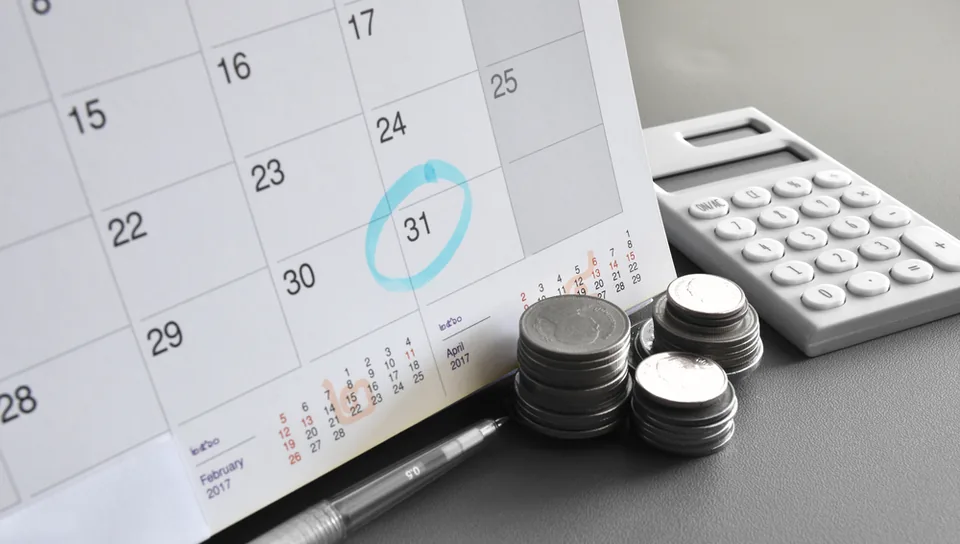 Calendar with the 31st circled beside a calculator and stacked coins