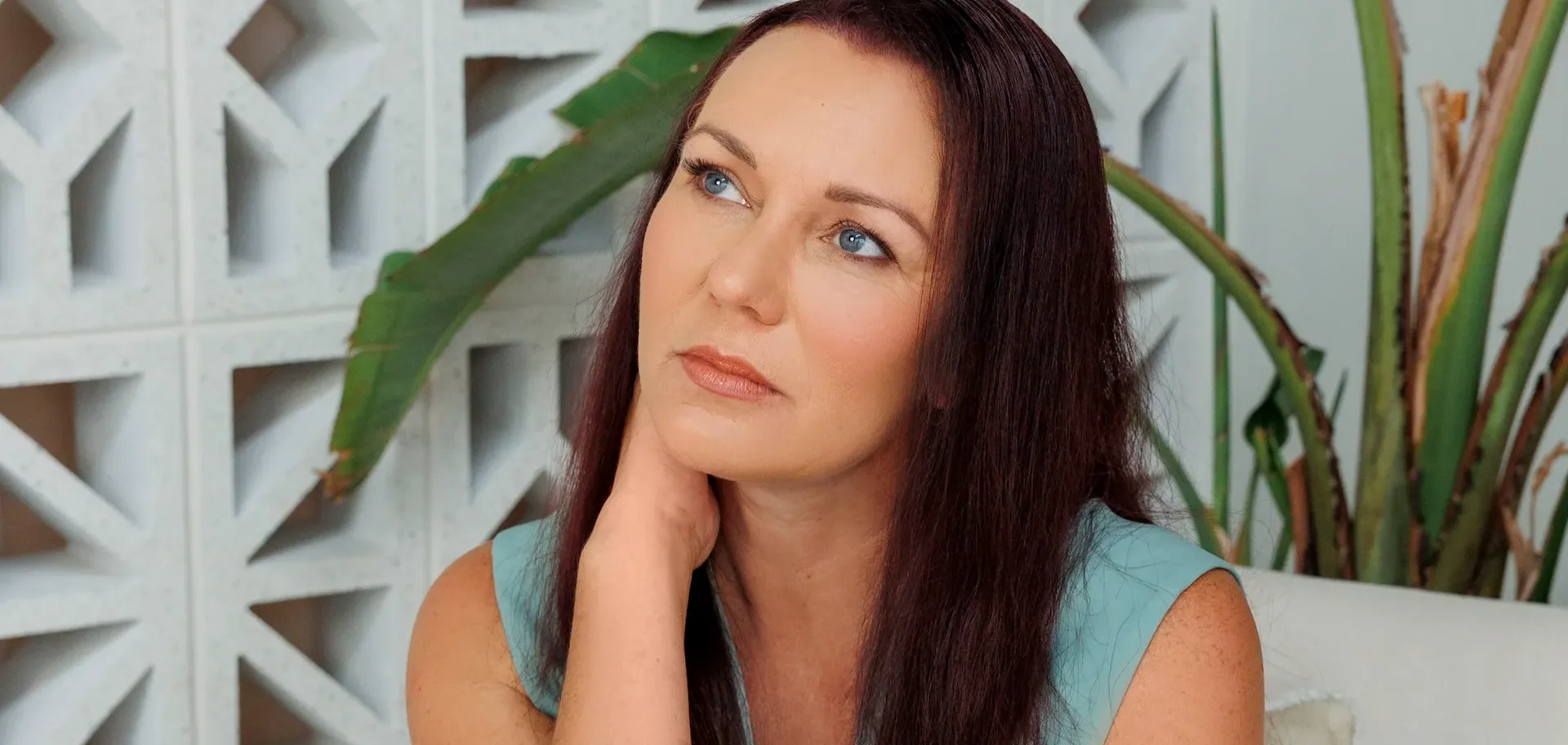 Jennifer O'Shea, registered BAS Agent, seated beside plants in a light studio