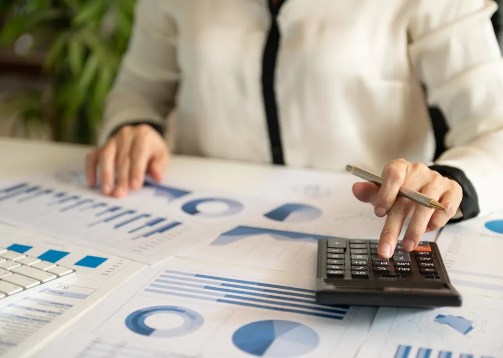 Accountant reviewing financial charts and account summaries with a calculator