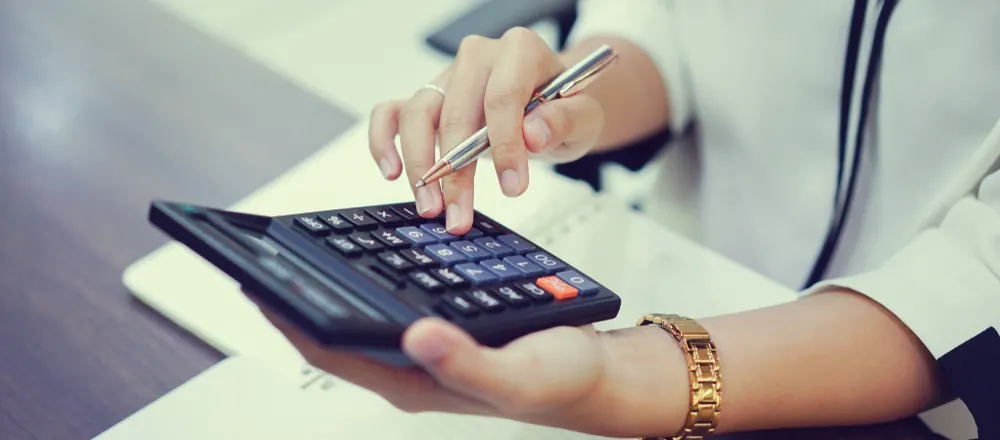 Hand using a calculator and pen over paperwork
