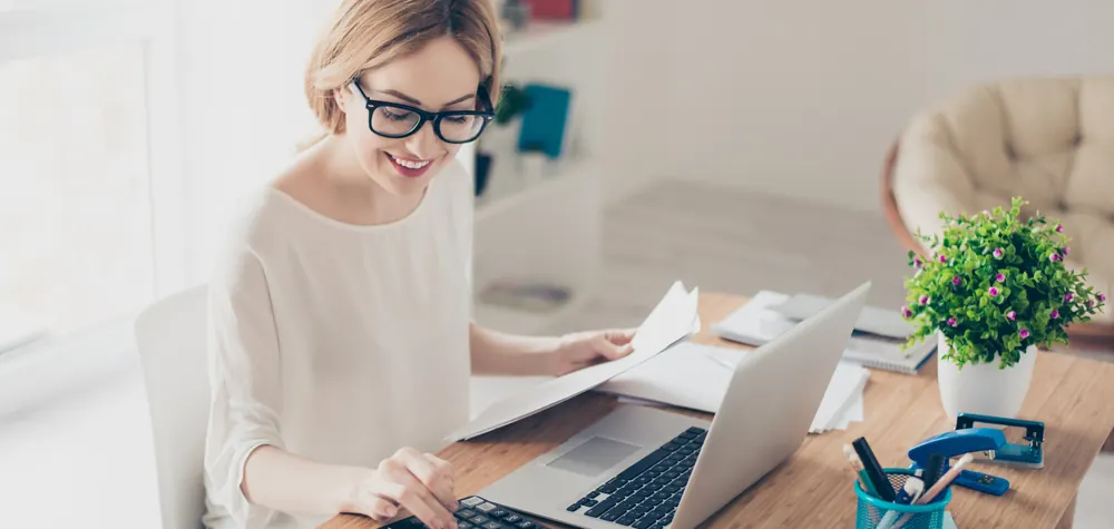 Business owner working at a laptop surrounded by paperwork